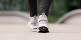 Close-up of person walking in gray sneakers