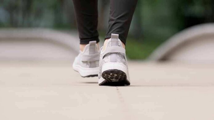 Close-up of person walking in gray sneakers