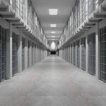 Prison corridor lined with barred cells on both sides