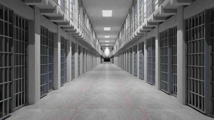 Prison corridor lined with barred cells on both sides