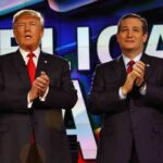 two men in suits clapping on a brightly lit stage