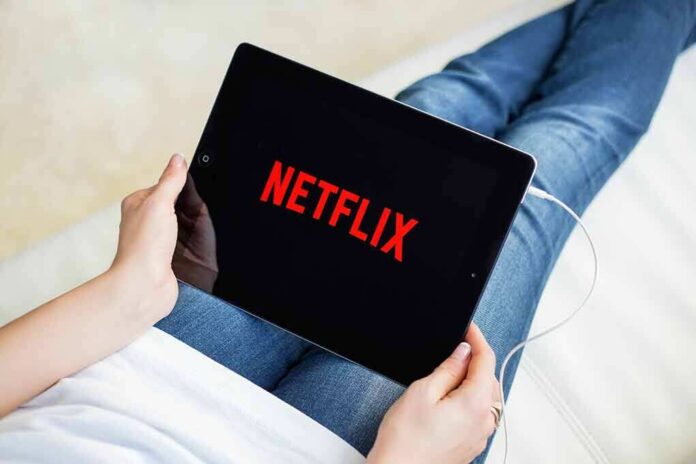 Person holding a tablet with streaming app on screen