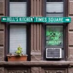 Apartment facade with windows, neon sign, and street direction sign