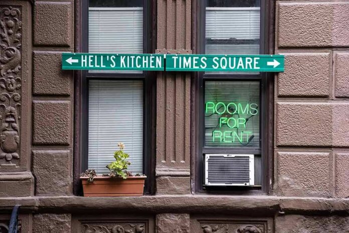 Apartment facade with windows, neon sign, and street direction sign