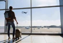 Traveler with suitcase watching plane through airport window