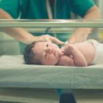 Newborn baby in hospital bassinet being cared for by nurse