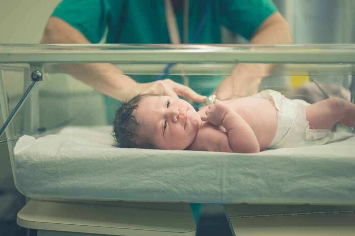 shutterstock_516260941 Newborn baby in hospital bassinet being cared for by nurse