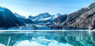 Boat approaching a glacier in a turquoise fjord