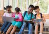 Children using laptops and tablets on school steps