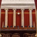 Empty courtroom with marble columns and red curtains