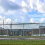 Prison yard behind chain-link and razor wire fence