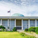 Parliament building with a green dome and flagpoles