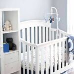 White baby crib with mobile in a bright nursery