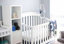 White baby crib with mobile in a bright nursery
