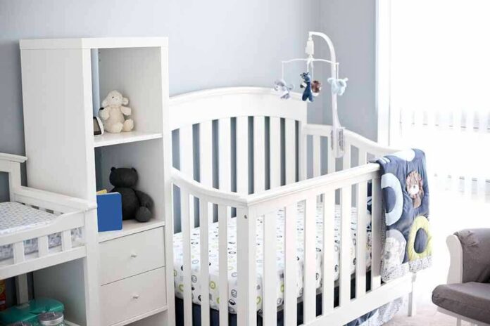 White baby crib with mobile in a bright nursery