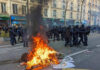 Fire burning on the street amid police presence.