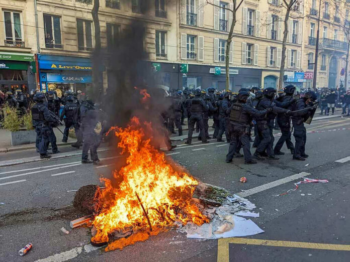 Fire burning on the street amid police presence.