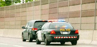 Police car with flashing lights stops a minivan on highway