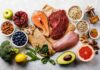 Assorted healthy foods with salmon, beef, chicken, fruits, vegetables, nuts, and grains