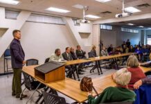 Roger Marshall addresses a community meeting with Apostolos Doxiadis among attendees