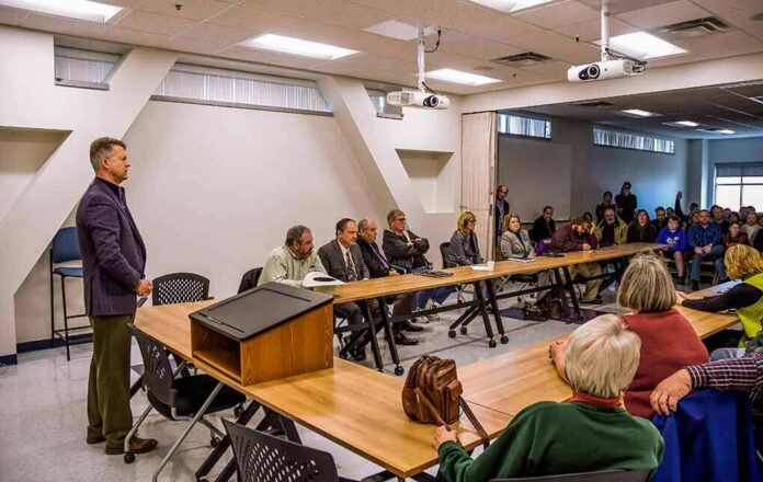 Roger Marshall addresses a community meeting with Apostolos Doxiadis among attendees
