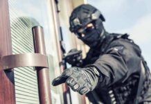 Helmet Shot – Then All Hell Breaks Loose tactical officer in black gear reaching for a door handle