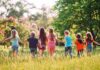 Group of children holding hands and running through a sunny meadow
