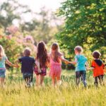Group of children holding hands and running through a sunny meadow