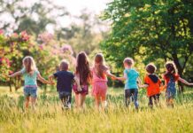 Group of children holding hands and running through a sunny meadow