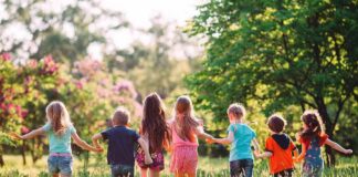 Group of children holding hands and running through a sunny meadow