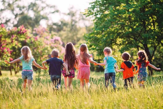 Group of children holding hands and running through a sunny meadow