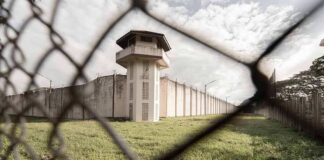 Prison watchtower behind chain-link fence