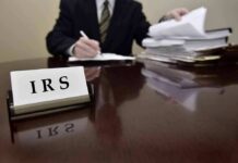 Two-Year Shock: Clergy Back Into Social Security IRS sign on desk with person reviewing documents