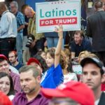 $6.6 Billion Going Into U.S. Submarine Production Child holding a 'Latinos for Trump' sign at a crowded rally
