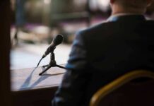 Microphone on a table near a seated person in a suit