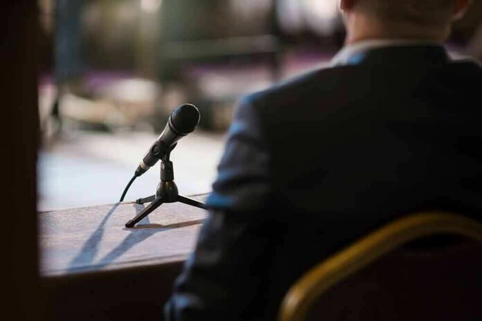 Microphone on a table near a seated person in a suit