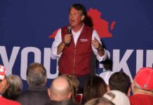 man speaking on stage at a rally
