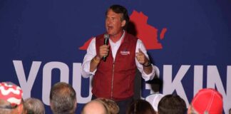 man speaking on stage at a rally