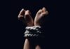 Hands bound with white rope against dark background
