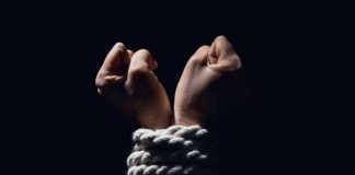 Hands bound with white rope against dark background
