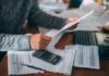20 Million Seniors Are Getting $90 Payments Person reviewing bills with calculator at cluttered desk