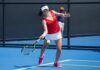 tennis player returning a ball on a blue hard court