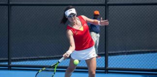 tennis player returning a ball on a blue hard court