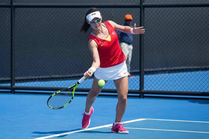 tennis player returning a ball on a blue hard court